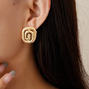 Gold square spiral earrings with hammer texture and metallic finish on model