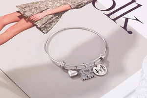 Detailed shot of silver stainless steel charm bracelet with I LOVE MOM pendants on a book