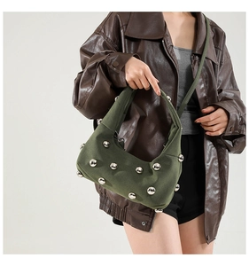 Detail of dark green crescent shoulder bag with metallic studs and suede texture