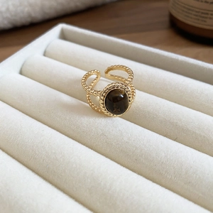 Detail of 18k gold plated tiger eye ring with vintage woven texture on white velvet stand