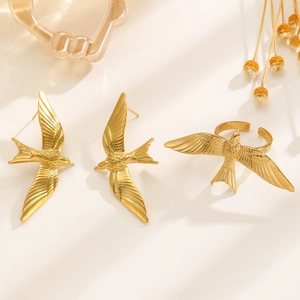 Detailed view of gold swallow jewelry set featuring engraved feathers on ring and earrings