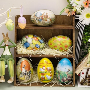 Easter tinplate egg storage containers with rabbit and floral motifs on a wooden shelf