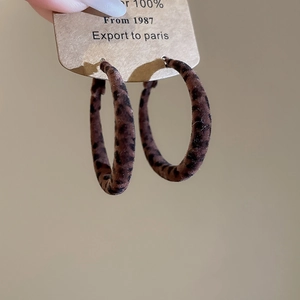 Gros plan de boucles d'oreilles géométriques léopard en velours sur carte kraft