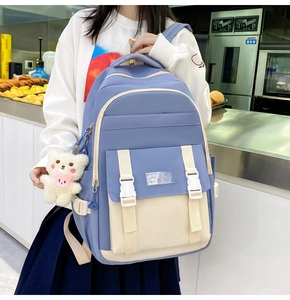 Blau-beiger Schulrucksack für Mädchen mit Bärenanhänger, präsentiert am Model