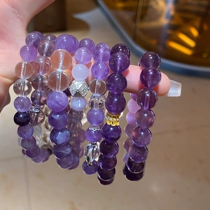 Macro detail of layered amethyst and clear crystal beaded bracelets with metallic charms
