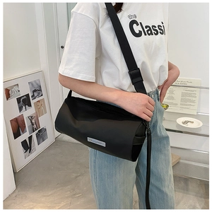 Détail d'un sac cylindrique noir en nylon avec bandoulière réglable sur un mannequin