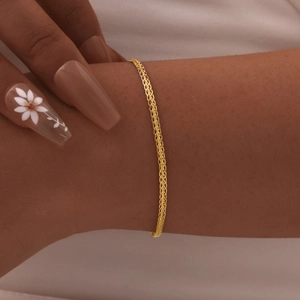 Macro detail of the woven golden chain bracelet texture on a woman's wrist
