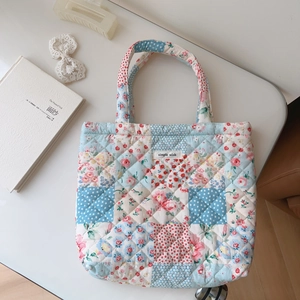 Detailed view of quilted patchwork tote with floral patterns and branded woven label
