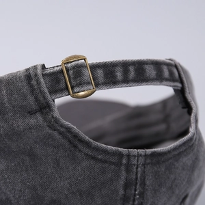 Detail of adjustable metal buckle on vintage washed black denim baseball cap texture