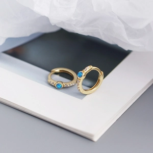 Macro shot of gold hoop earrings featuring blue opal stones and clear cubic zirconia accents