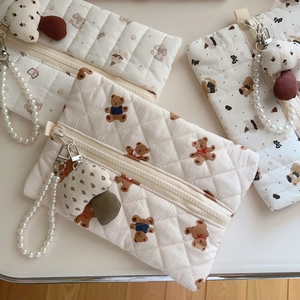 Detailed shot of quilted bear print pouches featuring pearl chain handles and mushroom charms