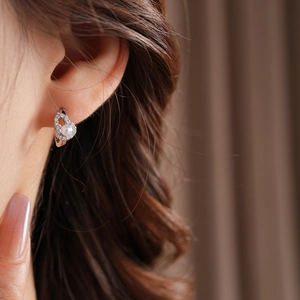 Close-up of a silver earring featuring sparkling zircon and a round white pearl on ear
