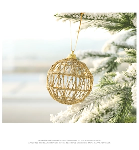Close-up of golden hollow Christmas ball ornament hanging on a snowy pine branch