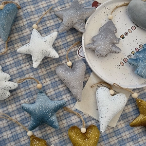 Detailed view of plush heart, star, and tree ornaments with silver glitter and wooden beads