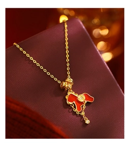 Macro detail of gold plated necklace with red enamel horse pendant and tassel decoration