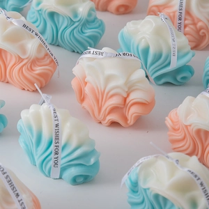 Detail showing the geometric wave texture and soft gradient colors of the scented candles