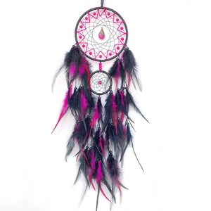 Handmade dreamcatcher with pink mesh and black feathers hanging on a white background