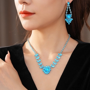 Close-up of elegant bridal jewelry set with blue heart crystals and leaf patterns on model