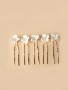 Detail of five white ceramic flower hair pins with gold U-shaped metal clips and crystals
