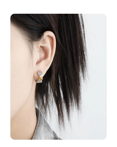 Close-up of knot-shaped S925 silver earrings with two-tone silver and gold plating