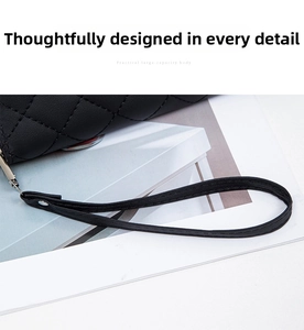 Close-up of black quilted leather clutch with metallic zipper and butterfly charm