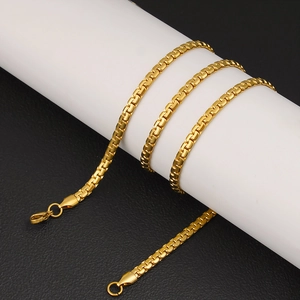 Detail of a 6mm gold stainless steel flat box chain wrapped on a white cylinder stand