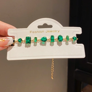 Close-up of gold bracelet with multi-shape green crystals and adjustable chain