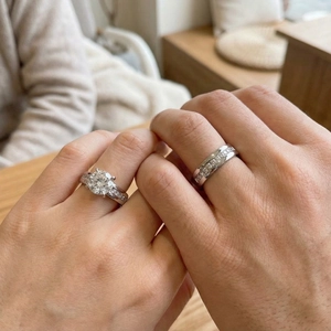 Close-up of couple's silver titanium steel rings with zircon settings on hands