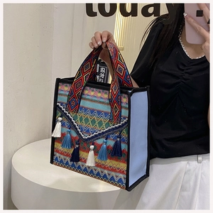 Close-up of ethnic woven bucket bag with blue tassels and boho patterned straps