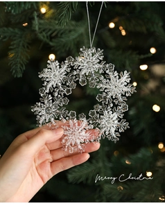 Close-up of transparent acrylic snowflake wreath ornament with glitter held by hand