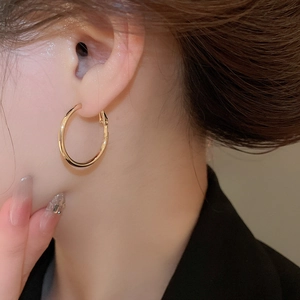Close-up of minimalist gold circular hoop earrings featuring a polished metallic finish