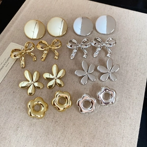 Vue de 8 paires de boucles d'oreilles fleurs et nœuds en or et argent sur tissu