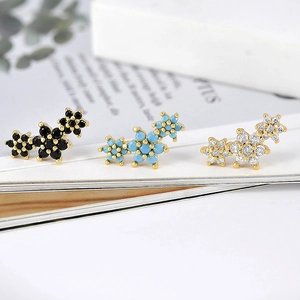 Detailed macro view of colorful zircon stud earrings with gold bases in flower shapes