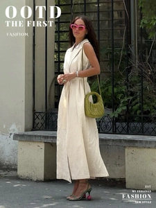 Detail of beige sleeveless shirt dress with lapel collar, waist belt, and side slit