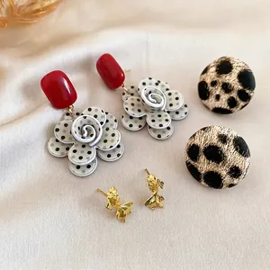 Detailed view of a 3-piece earring set featuring floral, leopard, and gold fish designs