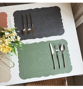 Detail of scalloped leather placemats with embossed patterns in grey and green colors