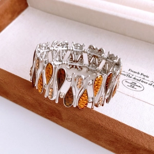 Macro detail of silver zircon bangle with amber resin drops in a jewelry box