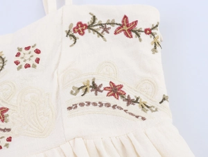 Detail of floral embroidery and pleated texture on a beige cotton linen summer dress