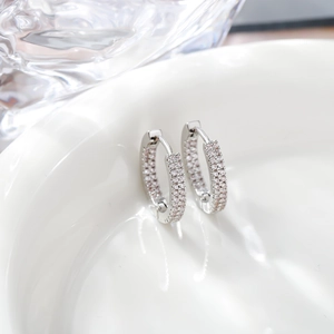 Detailed view of silver hoop earrings with triple-row pavé-set white zircons on white ceramic