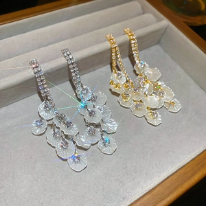 Détail de boucles d'oreilles à pompon dorées 18 carats avec zircon et pétales