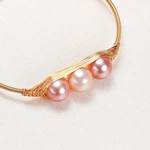 Elegant gold bangle with three pink gradient pearls handcrafted on textured white fabric