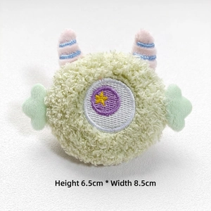 Green plush monster decoration with blue horns and star eye detail, size 6.5x8.5cm
