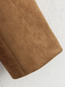 Vue macro détaillée de la texture du daim marron et des coutures de la manche du blouson