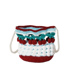 Detail of hand-crocheted bucket bag featuring 3D cherry motifs and faux pearl strap