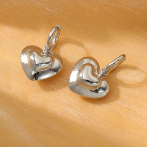 Polished silver heart drop earrings made of stainless steel on silk background