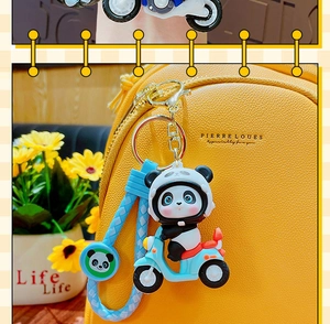 Detail of cute panda on blue scooter keychain attached to a yellow leather bag