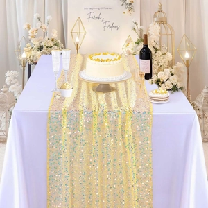 Detail of shimmering gold mermaid sequin table runner on a white tablecloth for weddings