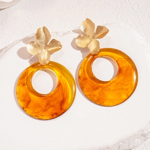 Flat lay of floral resin earrings with gold flower studs on white textured stone background