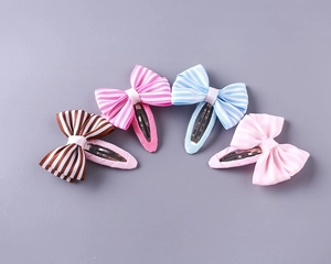Close-up of four striped grosgrain ribbon bow hair clips for girls in various colors