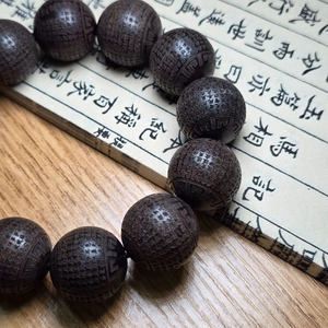 Détails macro des écritures bouddhistes gravées sur des perles de prière sombres